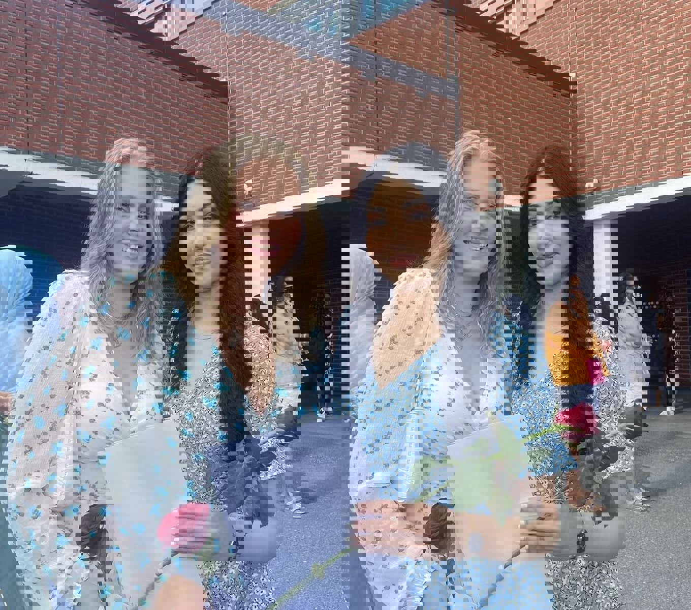 To jenter som holder en rose og vitnemål